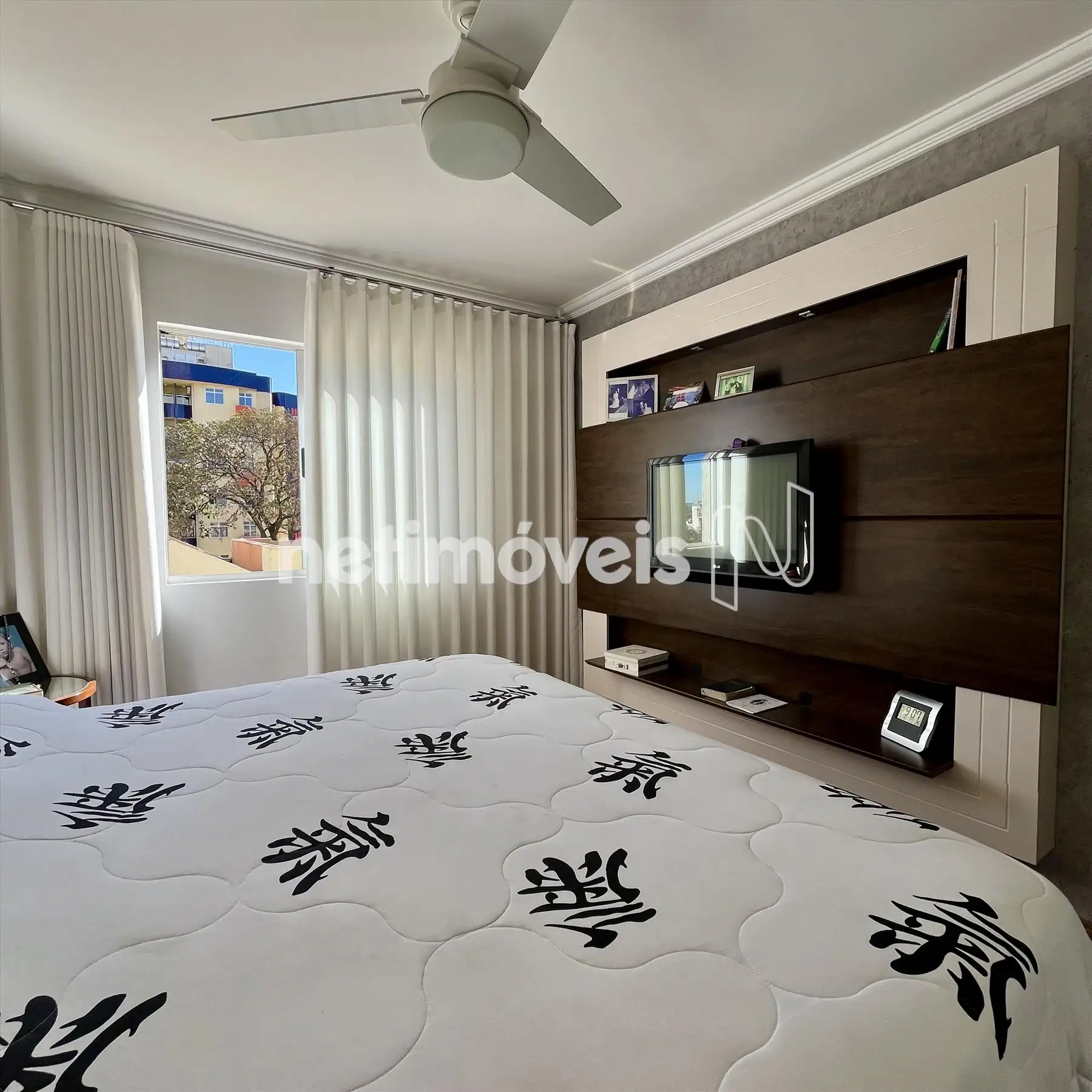 Suíte com painel de madeira e ventilador