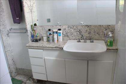 Suite com bancada em granito e armário.