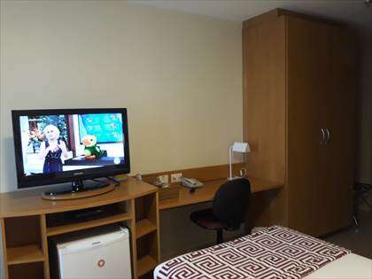 Banca de escritório, TV e frigobar.